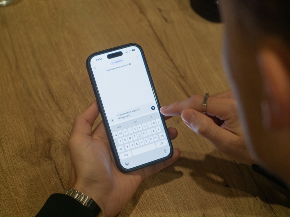Gebruiker die in ChatGPT een vraag stelt op zijn telefoon